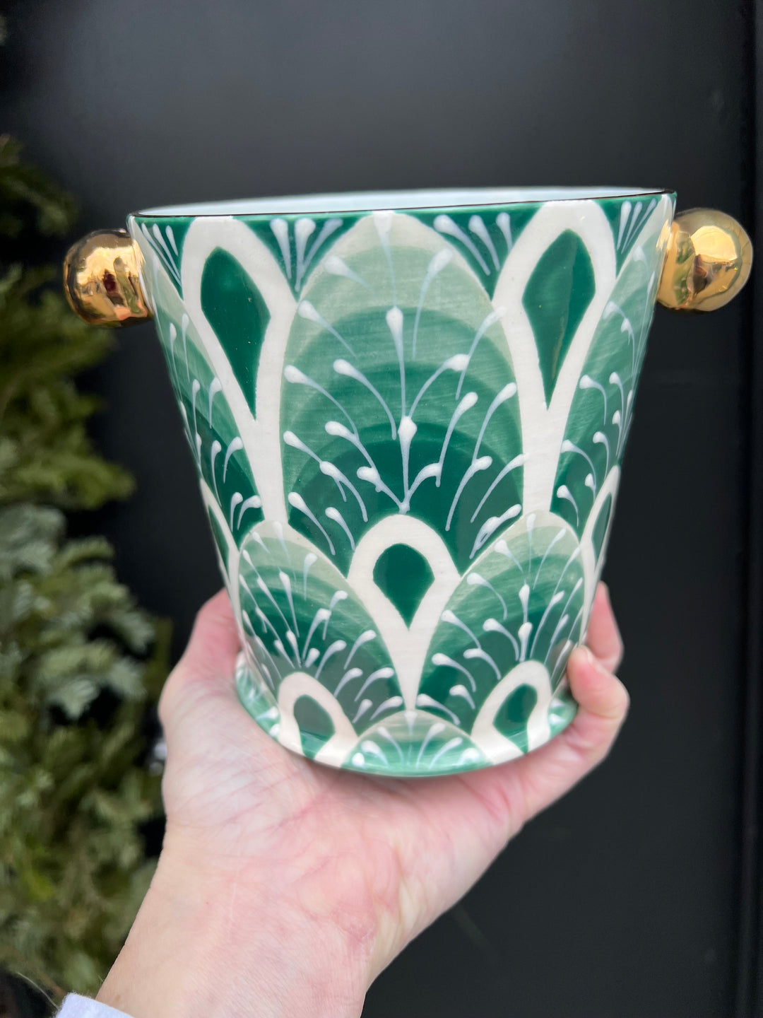 A small herb pot hand painted with a green feathery pattern and gold knobs and rim.