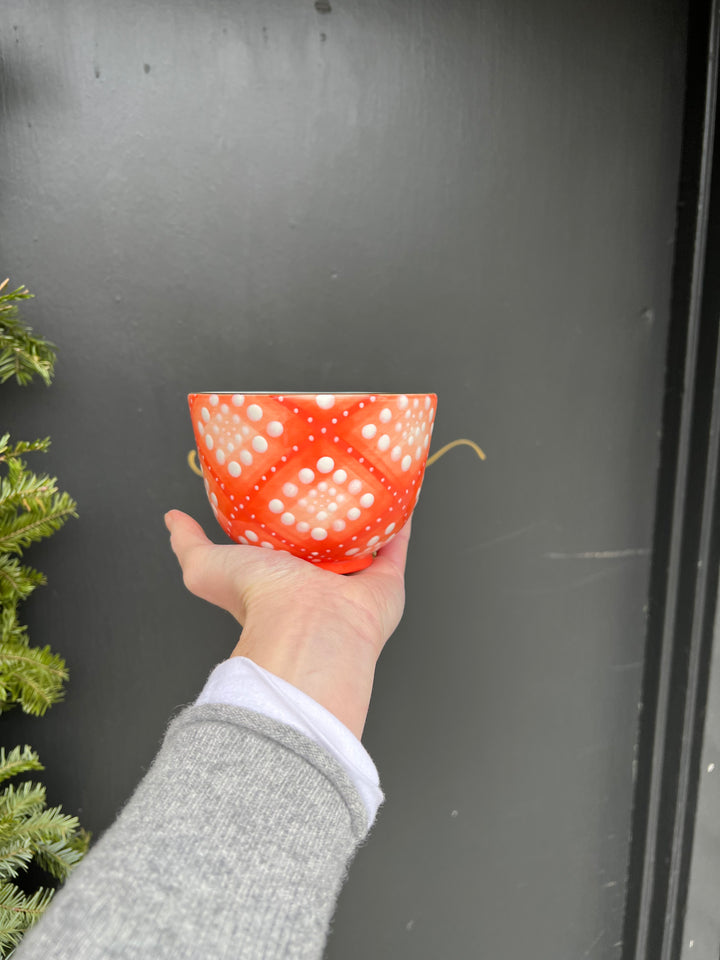 A dark reddish hand painted orange bowl with a bubble pattern and gold rim.