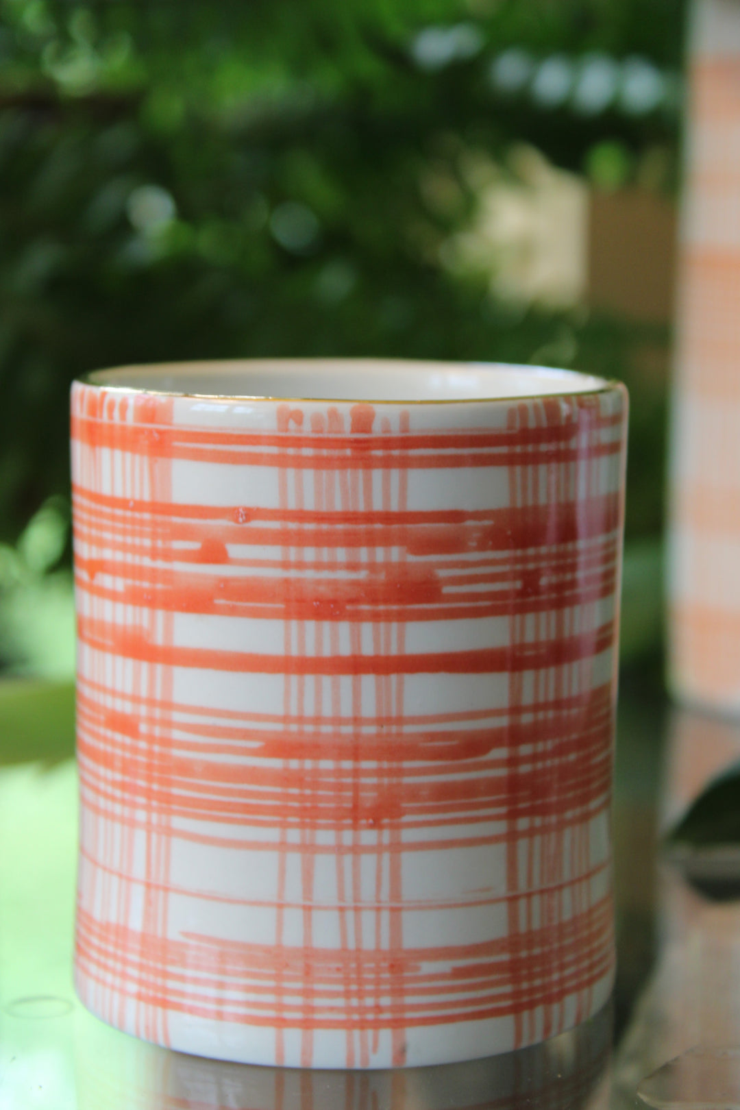 A small vase hand [painted with an orange pattern and gold rim.