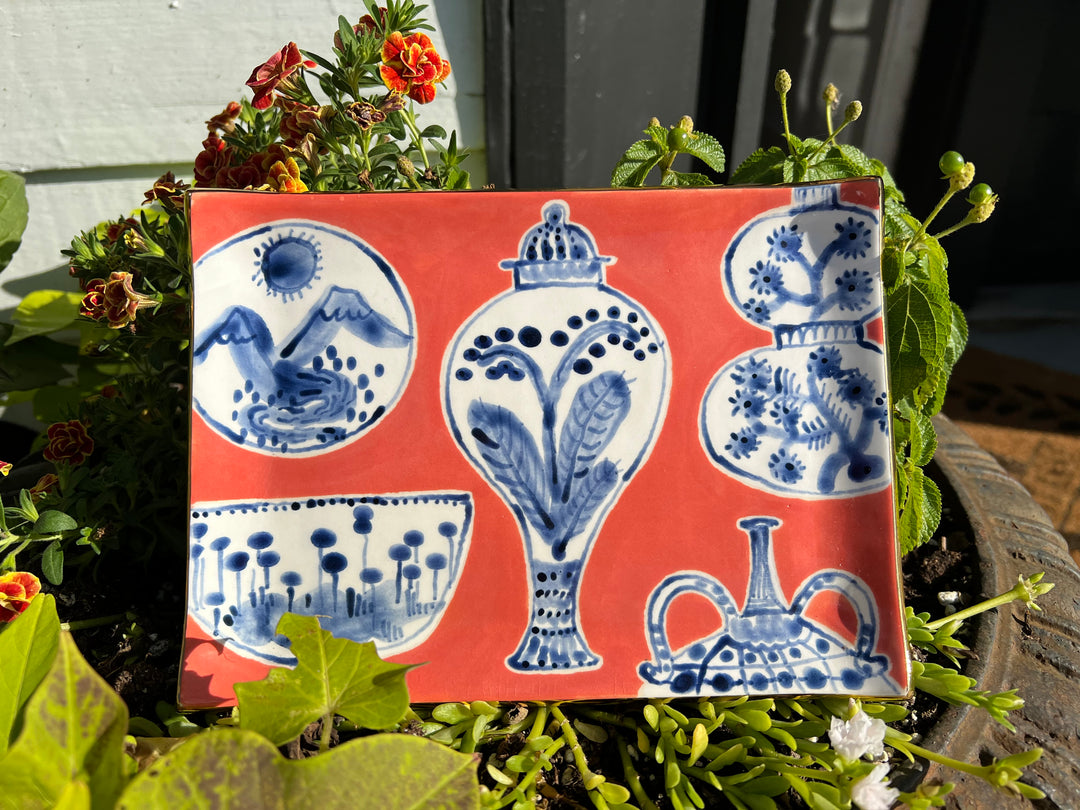Hand painted dark red/orange tray with blue and white vases and bowls and gold edging.
