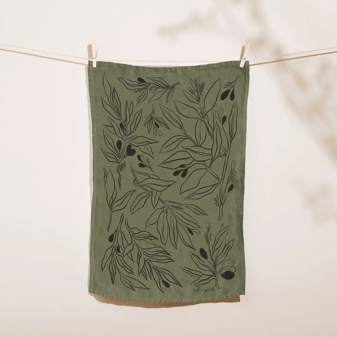 A dark green tea towel with design of dark olive branches complete with leaves and fruit.