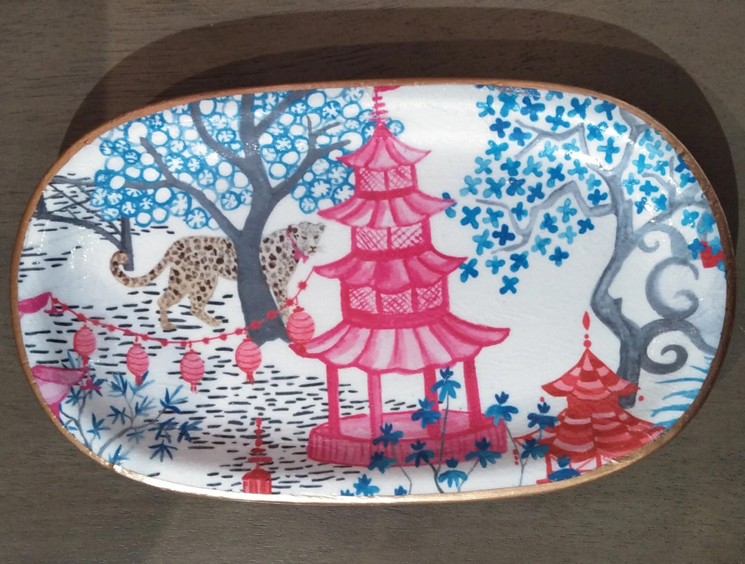 A decoupage ceramic tray with a pink pagoda and leopards.