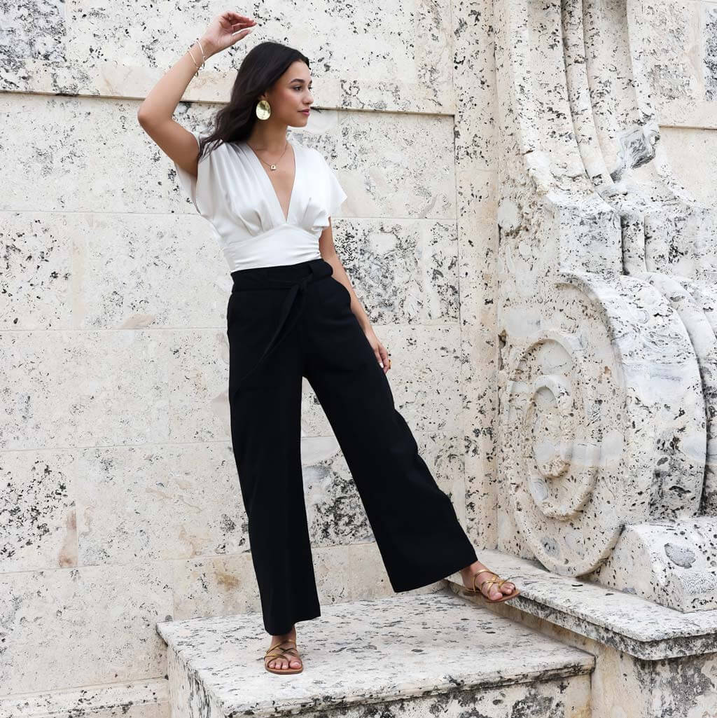 A lady stands on a marble step with a white blouse and black cotton wide leg pants,