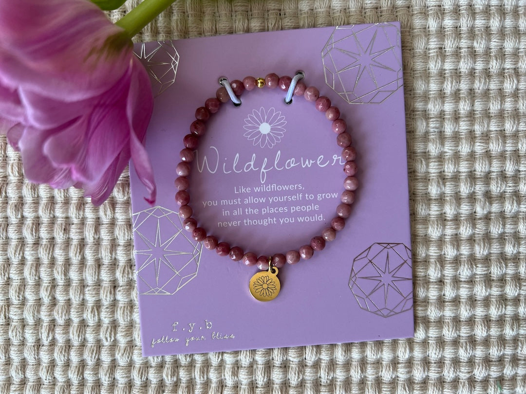 A pinkish red beaded charm bracelet on a card that reads "Wildflower."